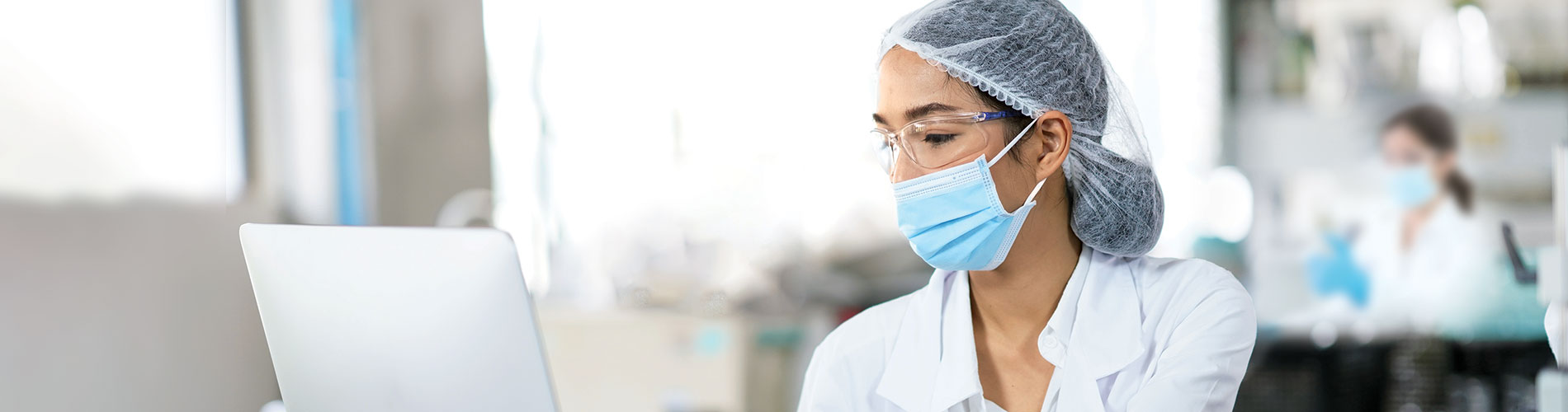 Scientist in a mask working on a laptop rna-qpcr-services